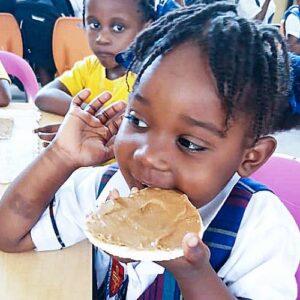 a young girl in Haiti eats bread with peanut butter as part of fftp school feeding programs
